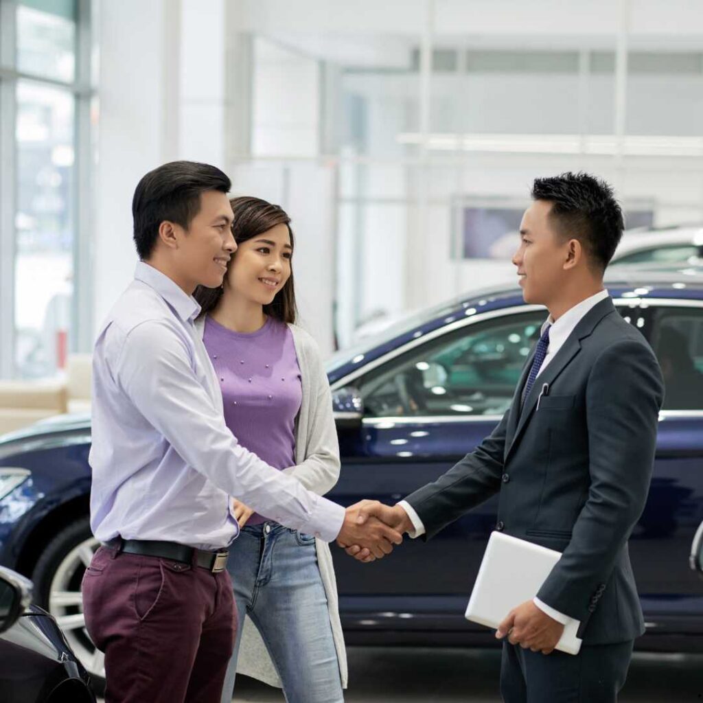 Sales mobil sedang salaman dengan customer pembeli mobil